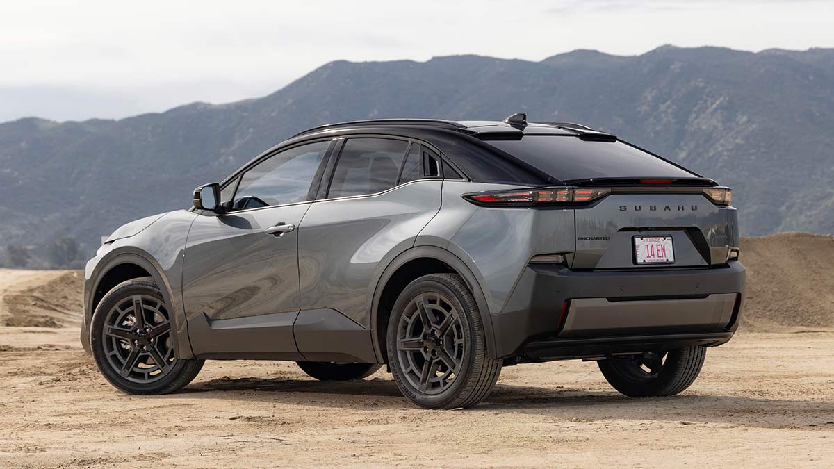 Rear-quarter view of grey Subaru Uncharted small electric SUV parked on gravel at high mountainous location.