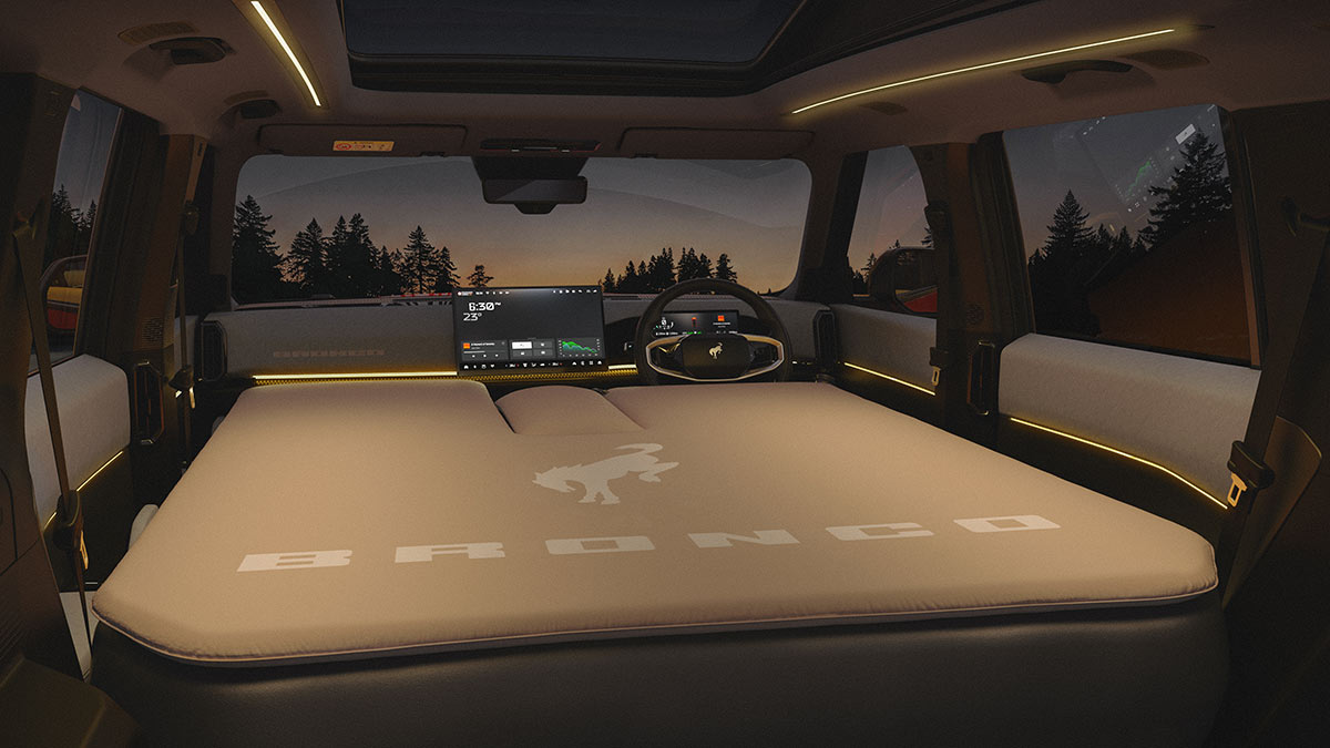 Optional custom-fit mattress laid out flat in cabin of Ford Bronco Basecamp parked in remote outdoors location at night.