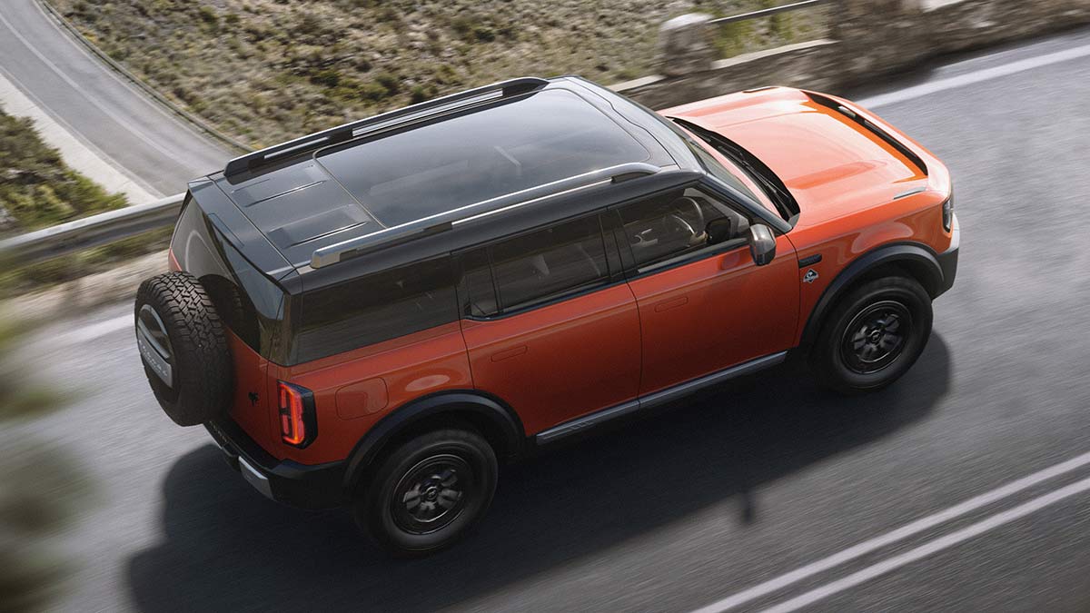 Overhead view of red Ford Bronco Basecamp SUV crossing bridge.