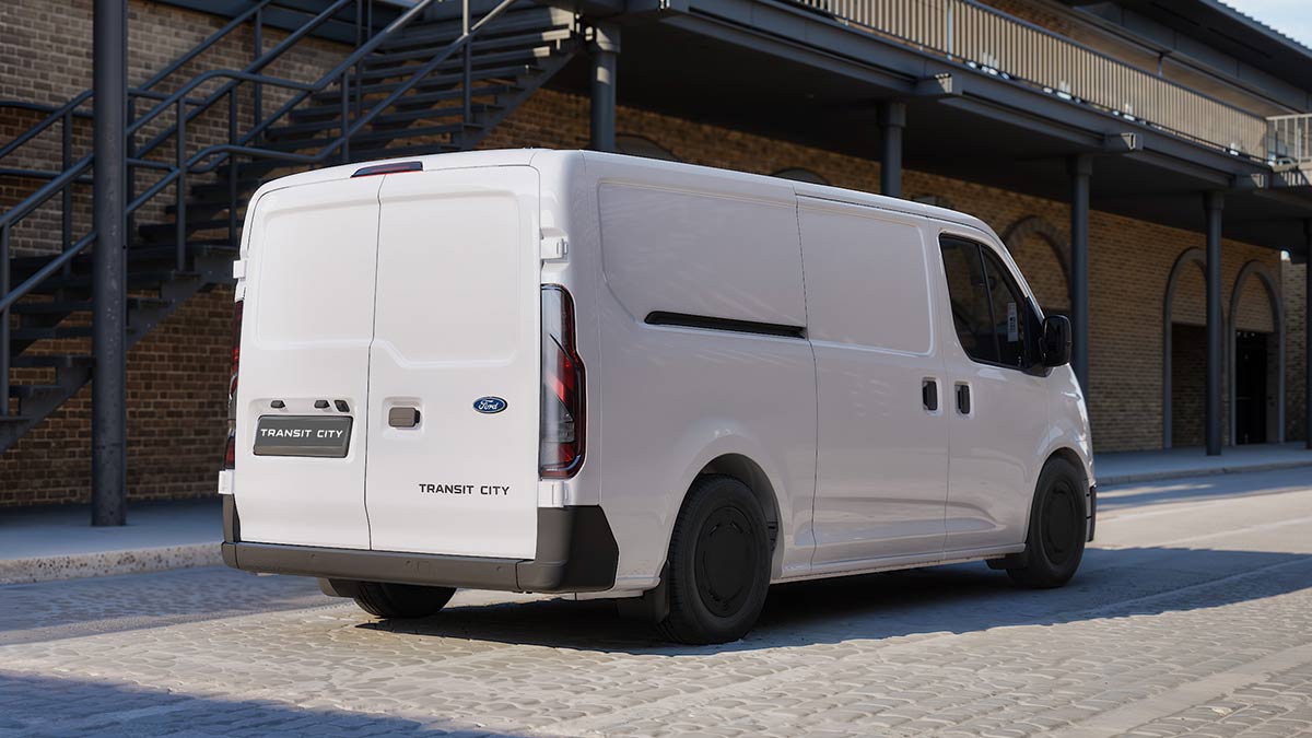 Rear view of white European-spec Ford Transit City van parked on brick-paved forecourt of double-storey heritage industrial building.