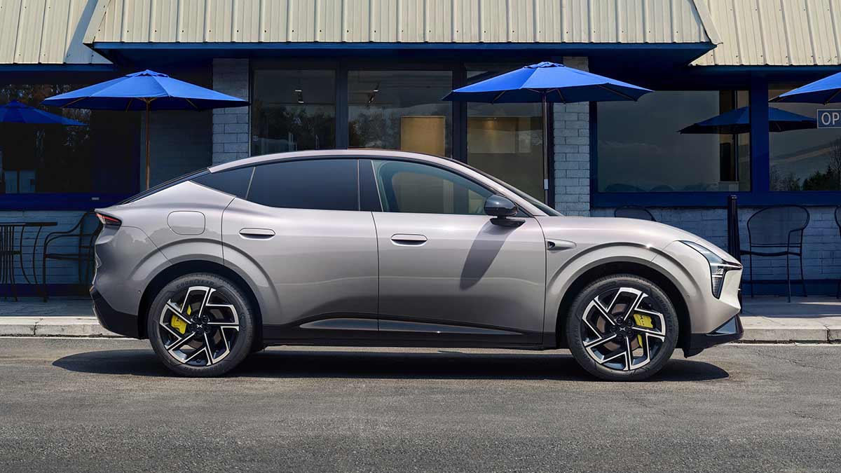 Profile shot of light grey XPeng L03 SUV parked outside brick building with blue outdoor umbrellas.