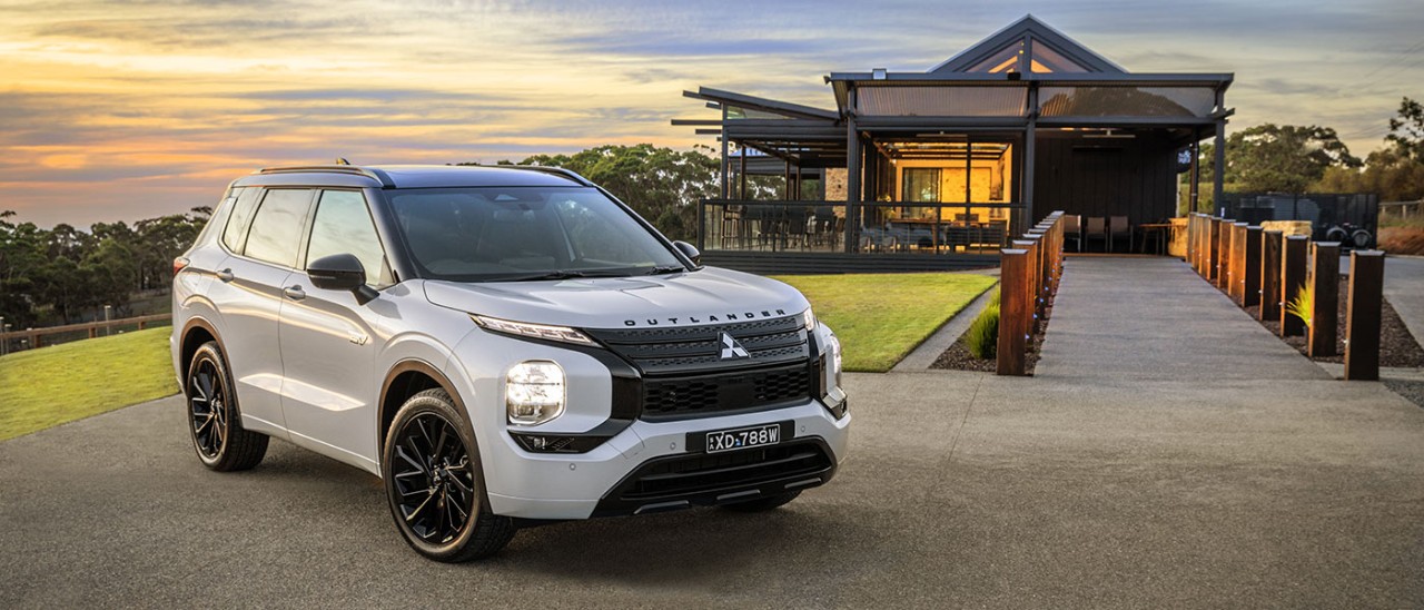 2024-Mitsubishi-Outlander-GSR-PHEV-front-banner-1400x600 White Mitsubishi Outlander GSR PHEV parked in front of building at sunset in rural location