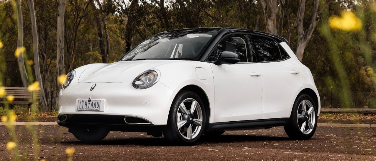 A white GWM Ora parked in a dirt carpark in the bush A white GWM Ora parked in a dirt carpark in the bush