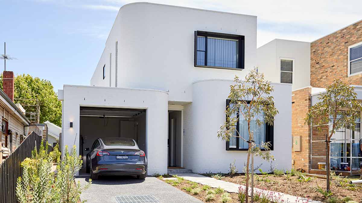 Blue Tesla EV parked at garage entrance of modern white suburban home in Melbourne