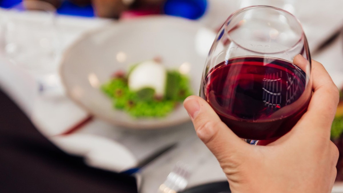 Person holding a glass of red wine