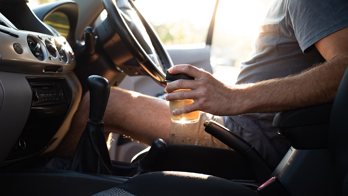 Man getting into car holding a cup of coffee