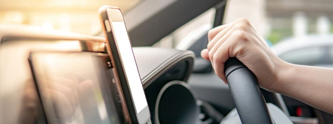 mounted smartphone in car next to hand on steering wheel