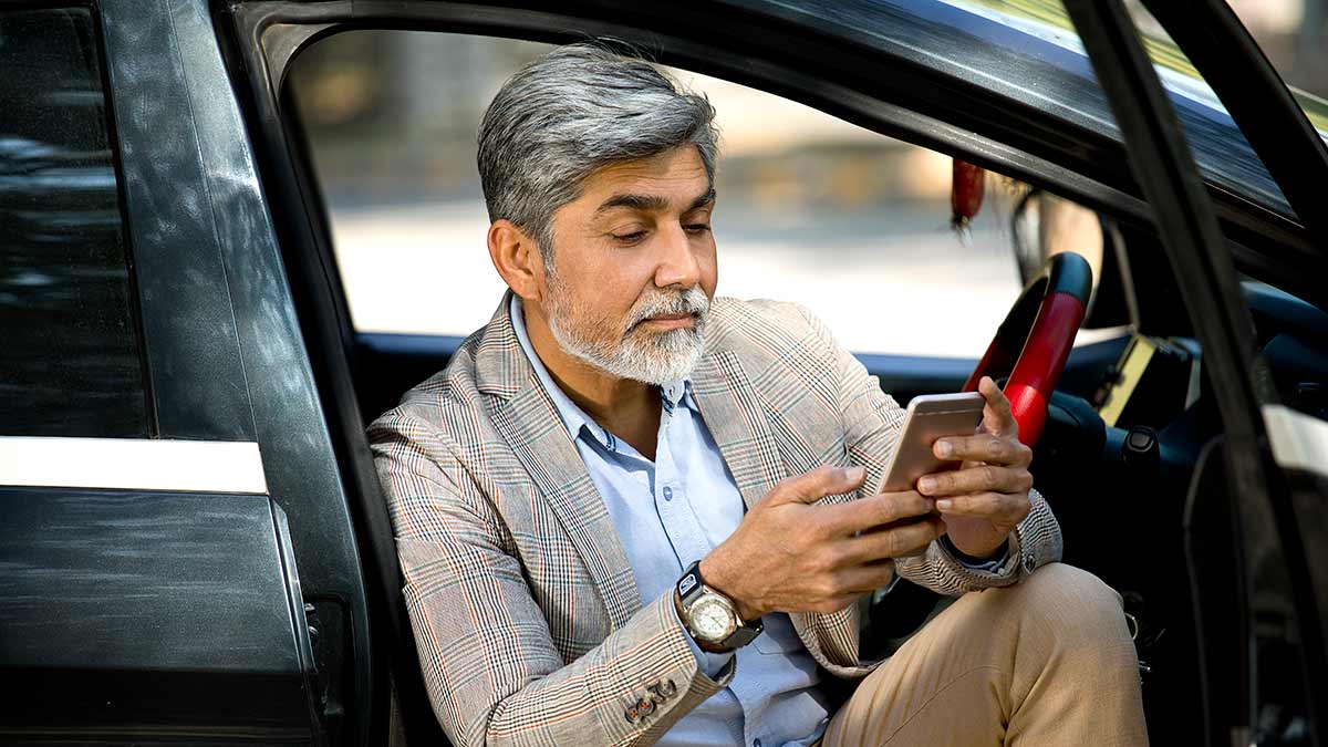 Person sitting in car with door open on mobile phone