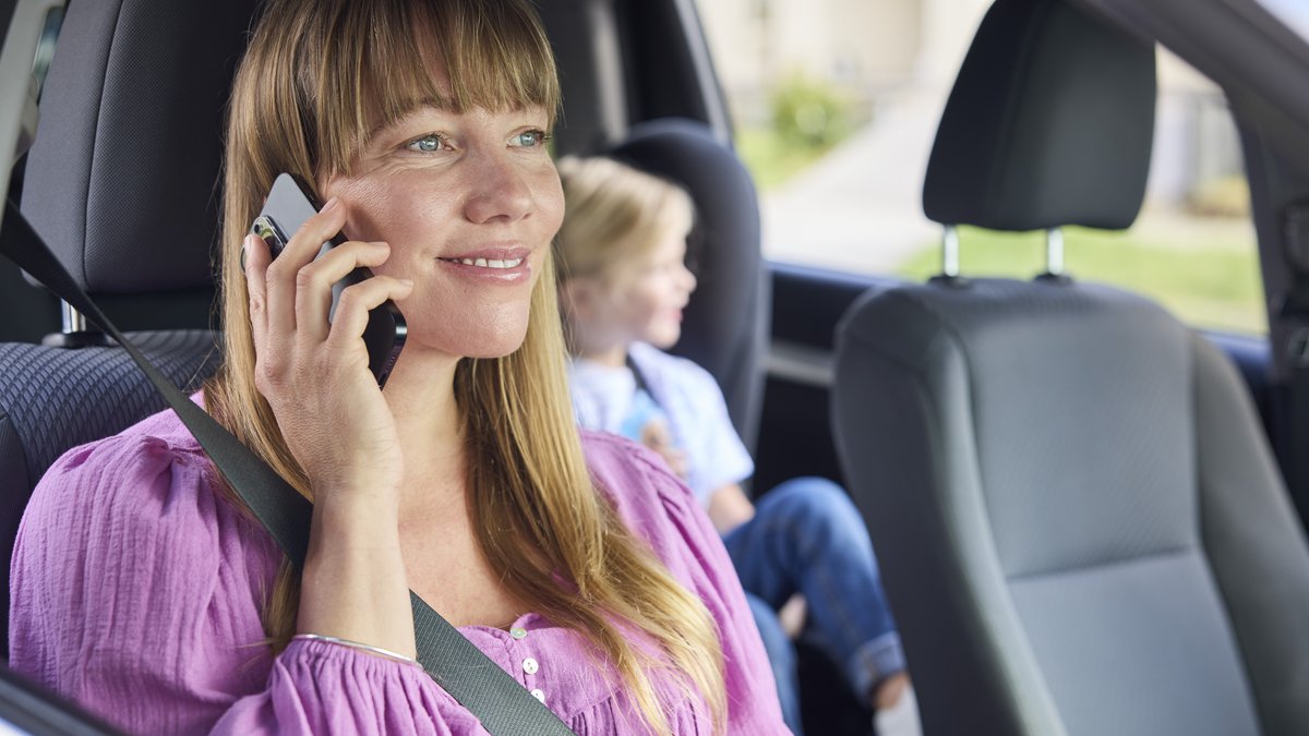 Person sitting in car with door open on mobile phone