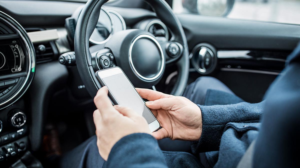 Person using mobile phone inside car while parked