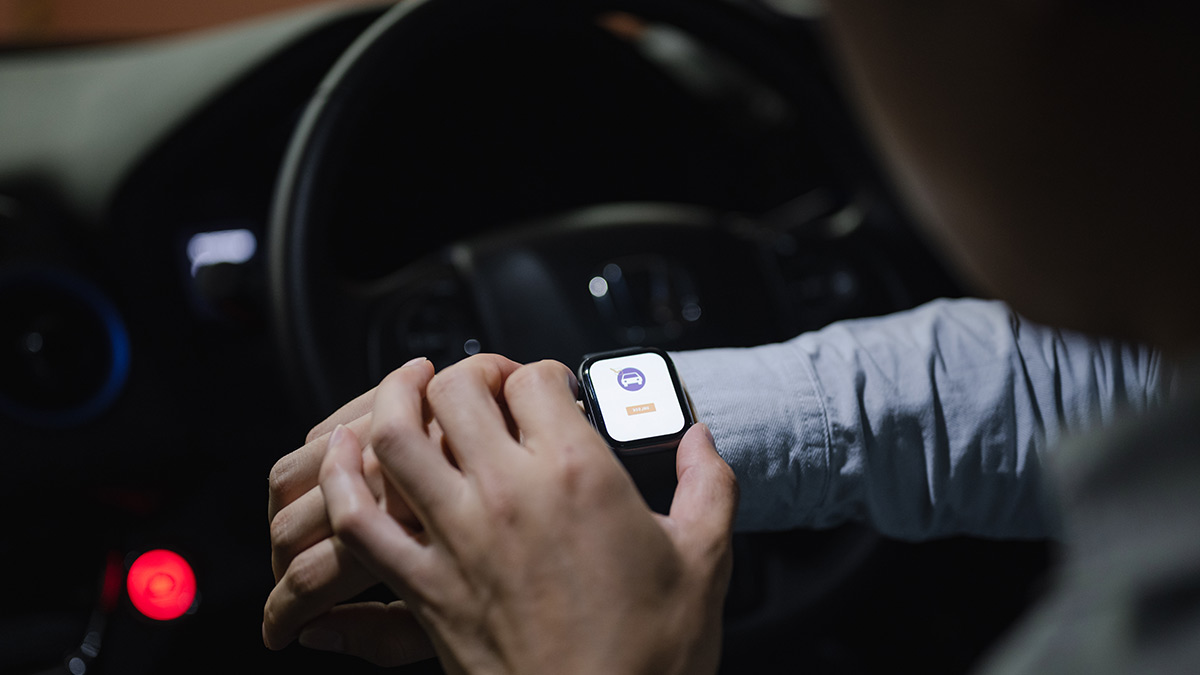 Person setting up smart watch inside car while parked