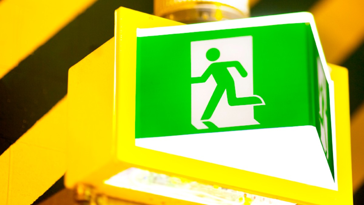 A person pressing a pedestrian crossing button while looking at their smartphone