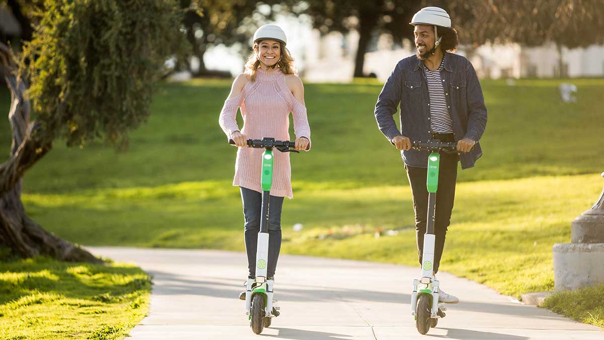 Couple riding escooters through the park