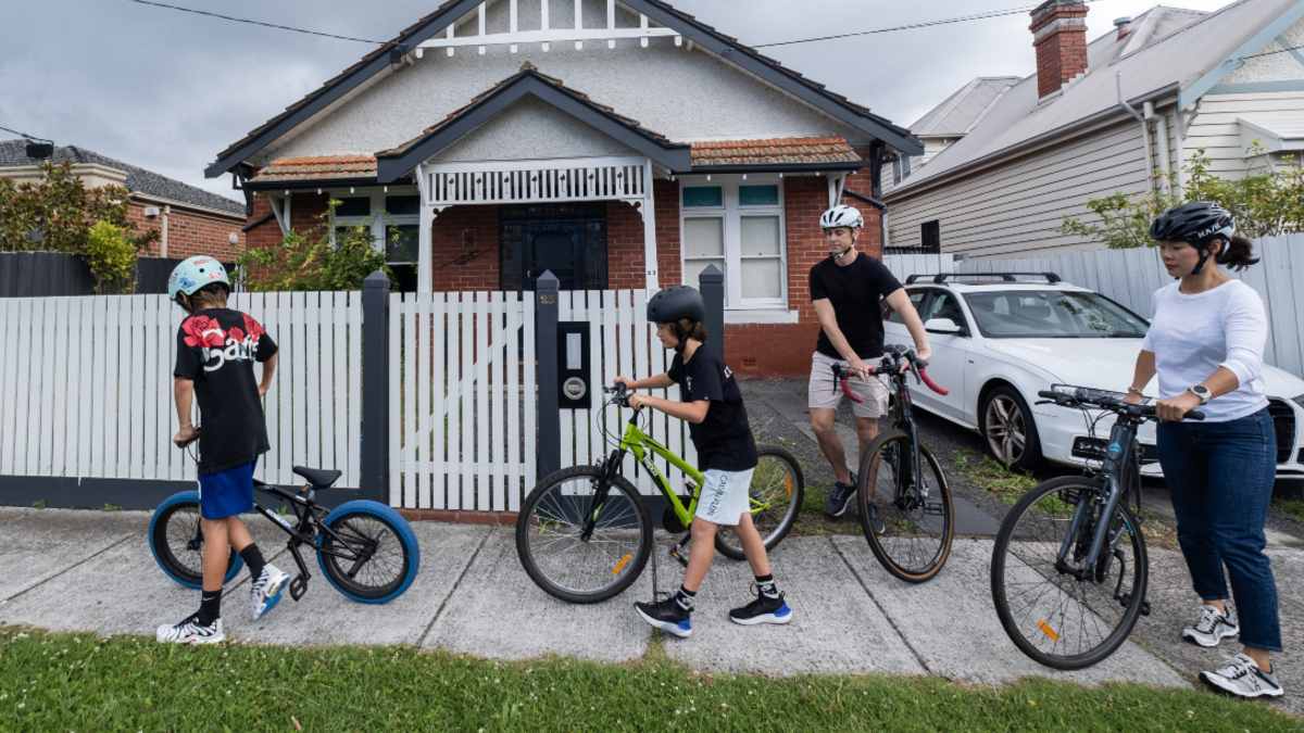 A family of two adults and two children setting out from their house to go cycling