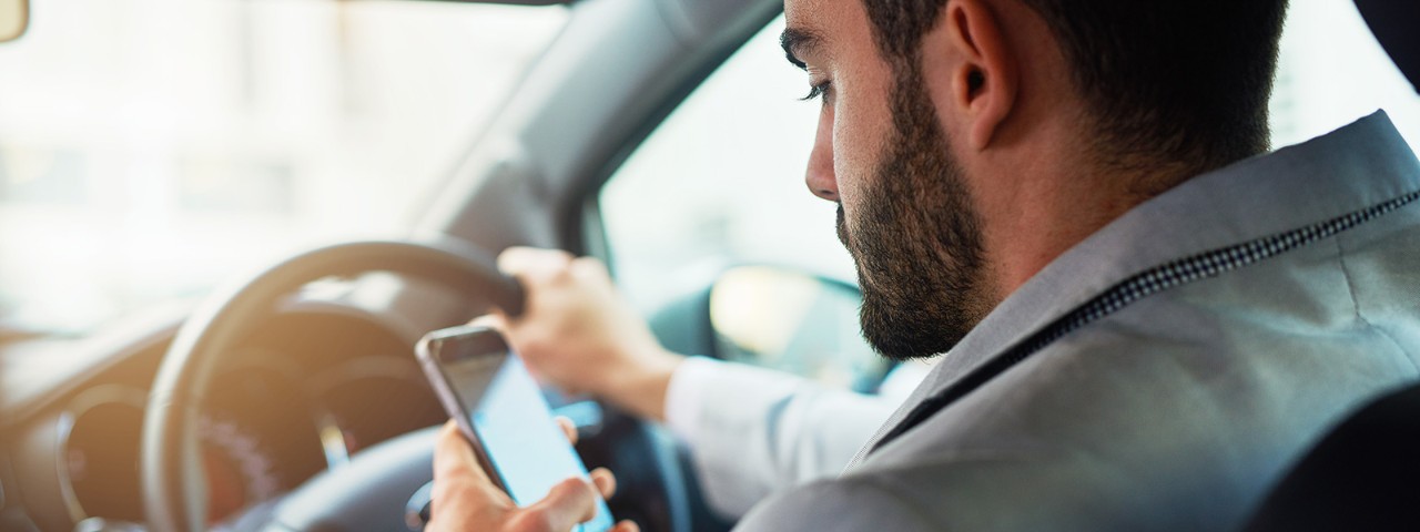 627539868 A man using a handheld mobile phone while driving.