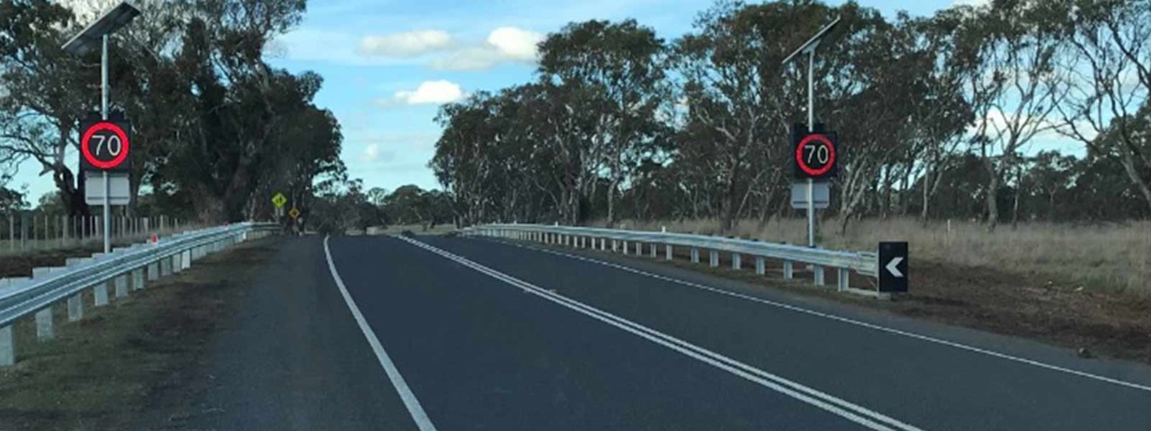 Country road with digital speed signs on the side.