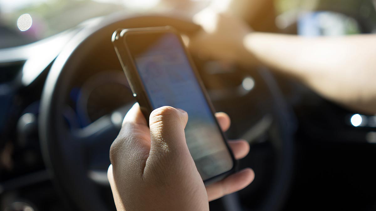Phone being held while driving, which is not recommended.