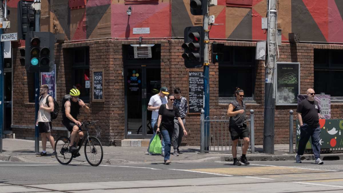 A person pressing a pedestrian crossing button while looking at their smartphone