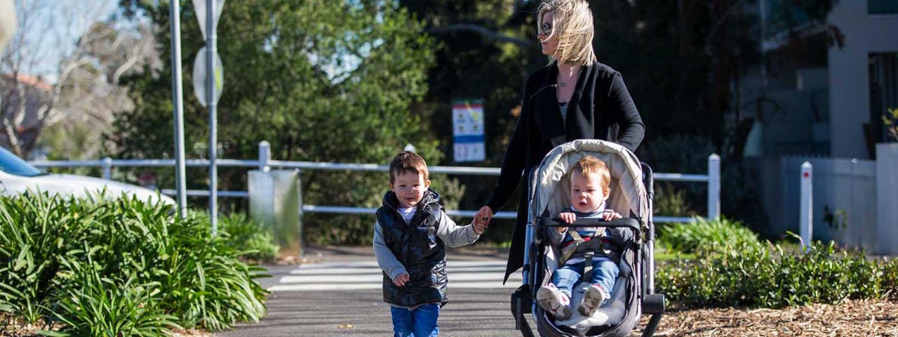 Mother with children and pram walking along path.