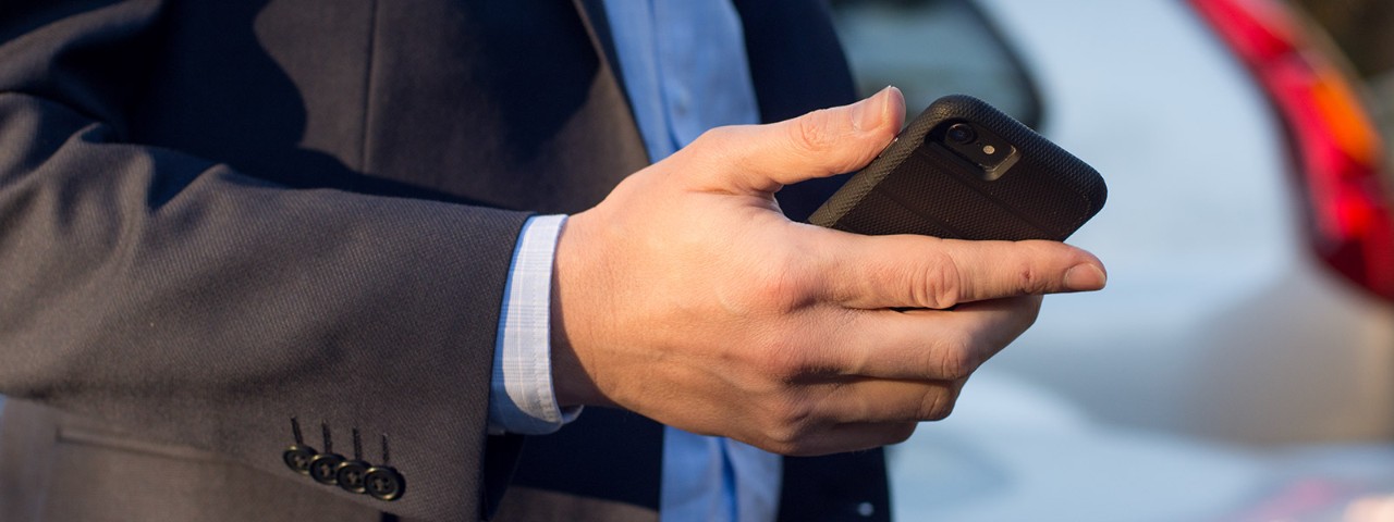1167461524 Man with phone next to car