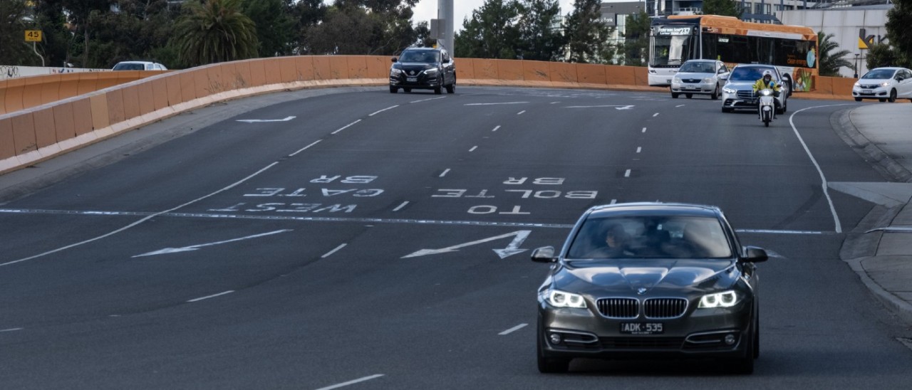 Cars driving along a four-lane road in Melbourne. Line markings and arrows are clearly visible