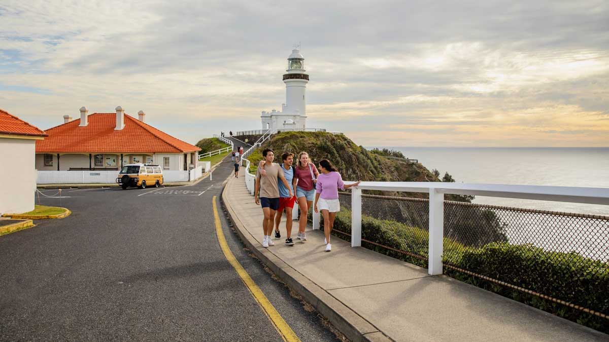 people walking along footpath in front of lighthouse