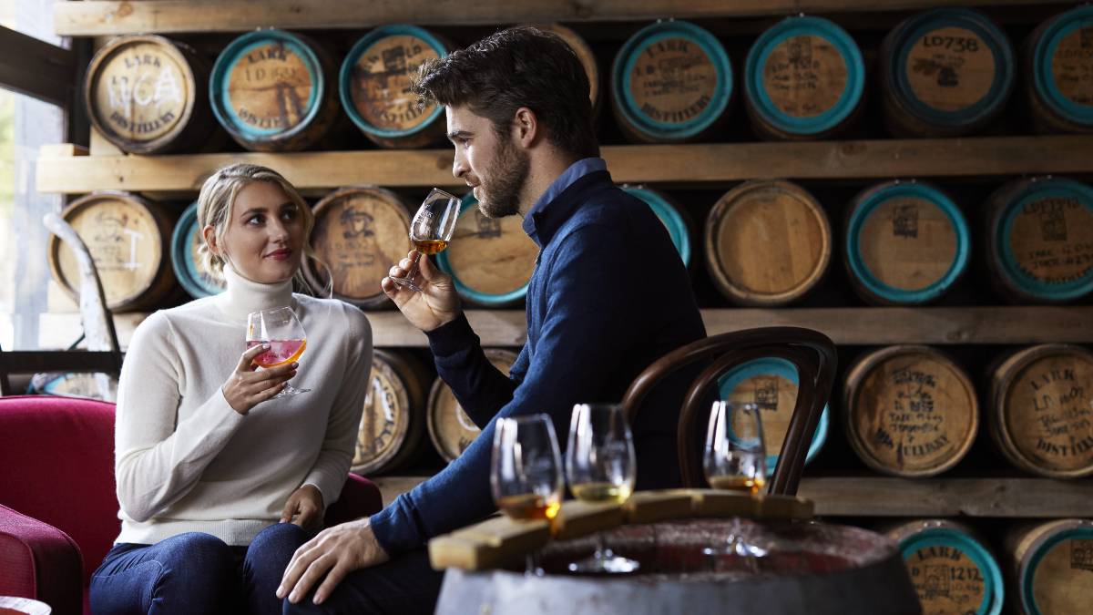 man and woman sipping whisky in a distillery