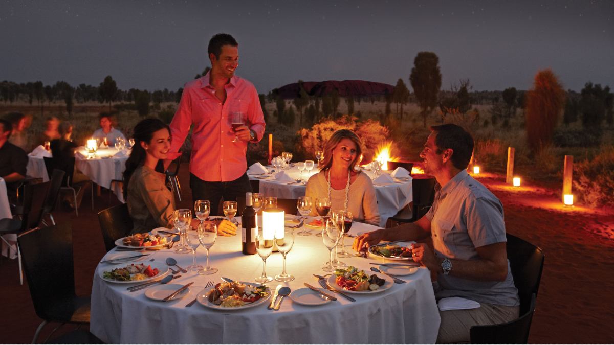 four people enjoying an outdoor dinner near Uluru