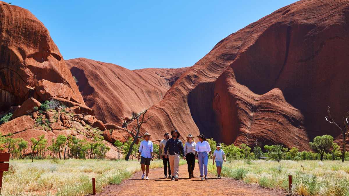 six people walking around Uluru's base
