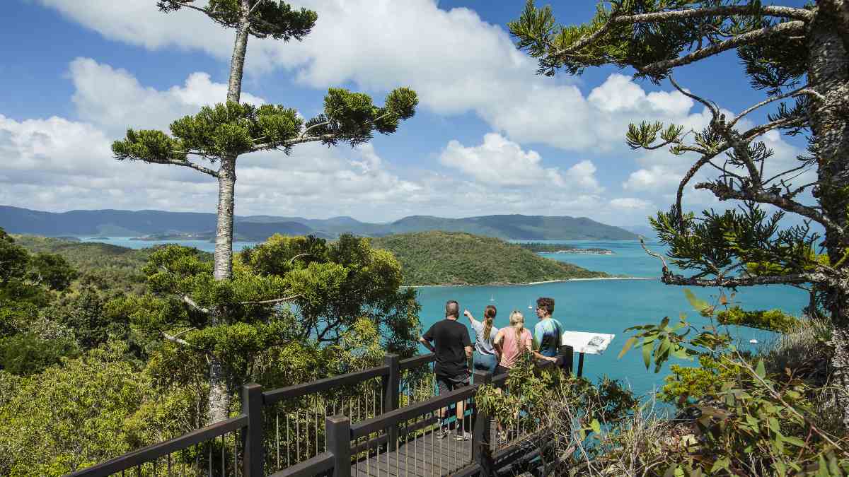 family of four standing at a lookout over rainforest and beach