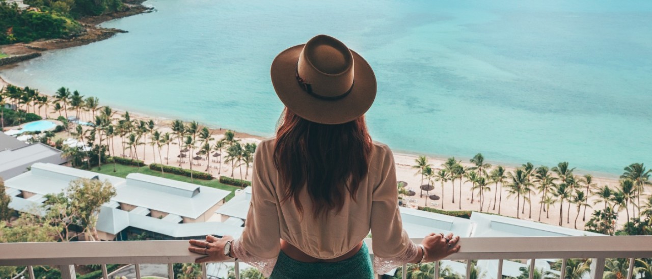 Hamilton Island, Whitsundays_Tourism and Events Queensland woman standing on hotel balcony looking at tropical beach