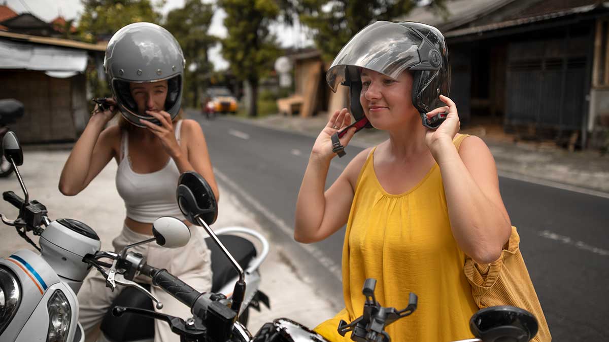 Two women putting helmets on before riding mopeds