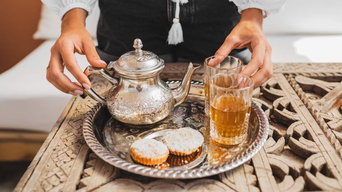 woman serving traditional mint tea with cookies in Morocco