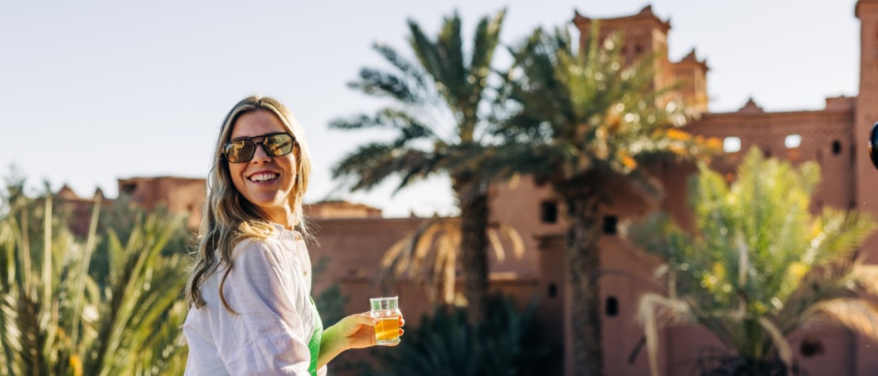 Morocco_Intrepid Travel young woman holding a drink on balcony overlooking Morocco