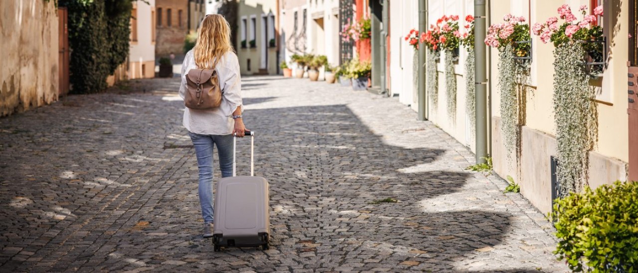 woman wearing backpack and taking suitcase up a cobbled street in Czechia