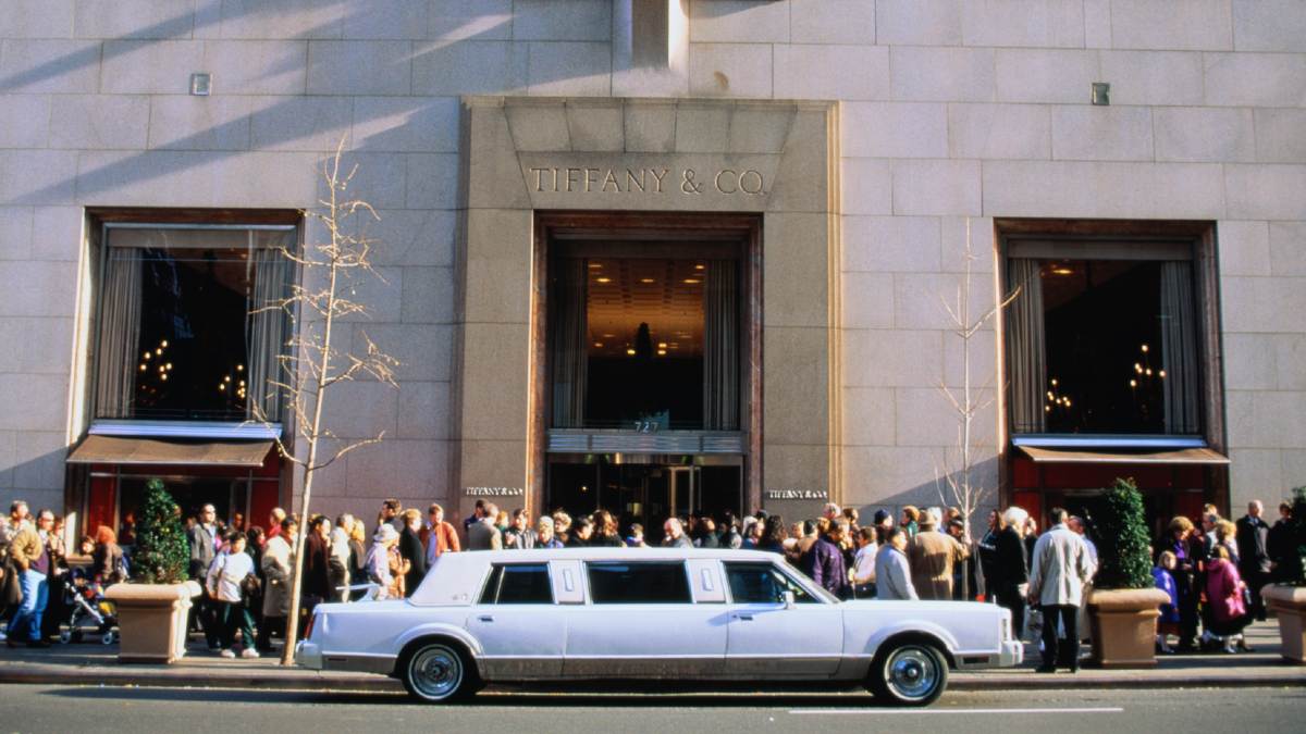 white limousine outside a stone building crowded with people