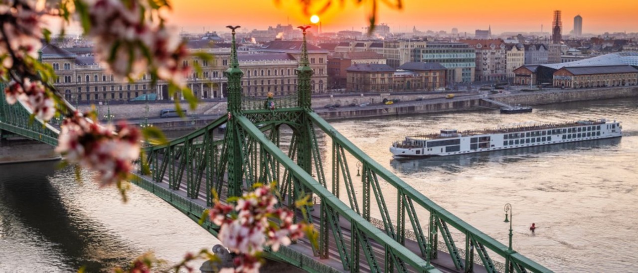 cruise ship on European river passing under bridge