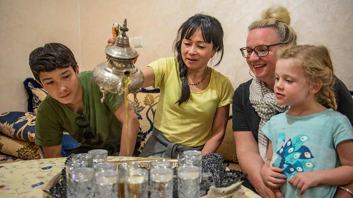 Two parents and their children watching tea being poured in Morocco.