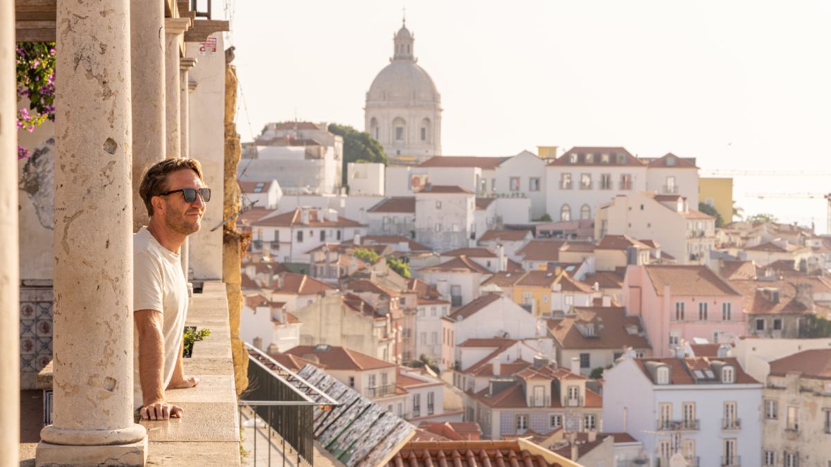 man looking out from balcony over Lisbon's Alfama district