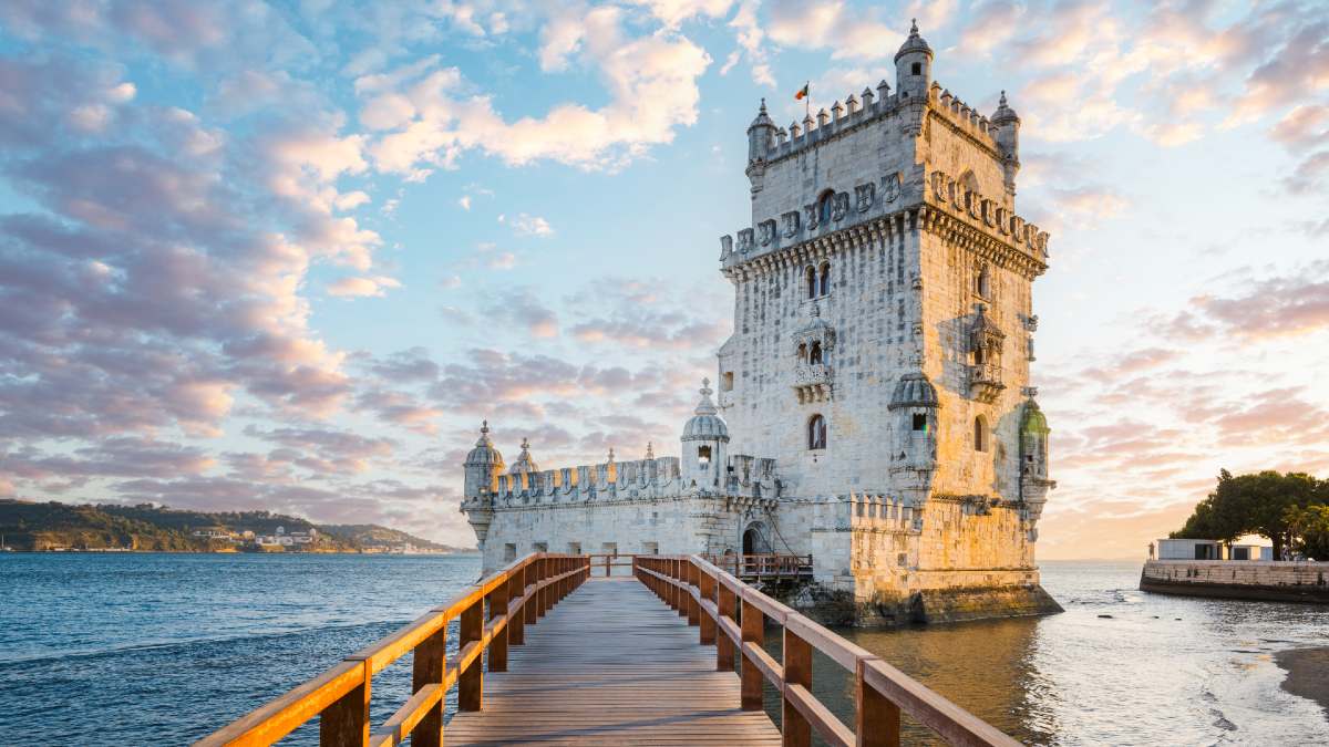 white tower rising from the sea with bridge leading to it