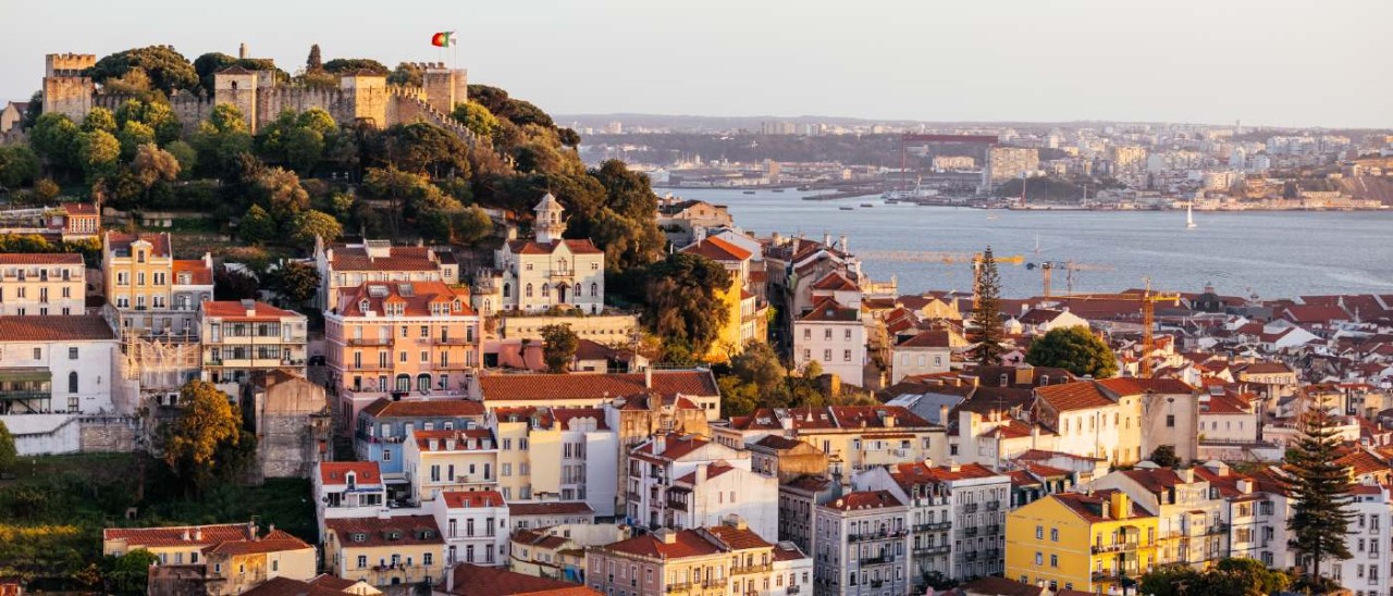 aerial view of Lisbon with castle on hill, river and many buildings