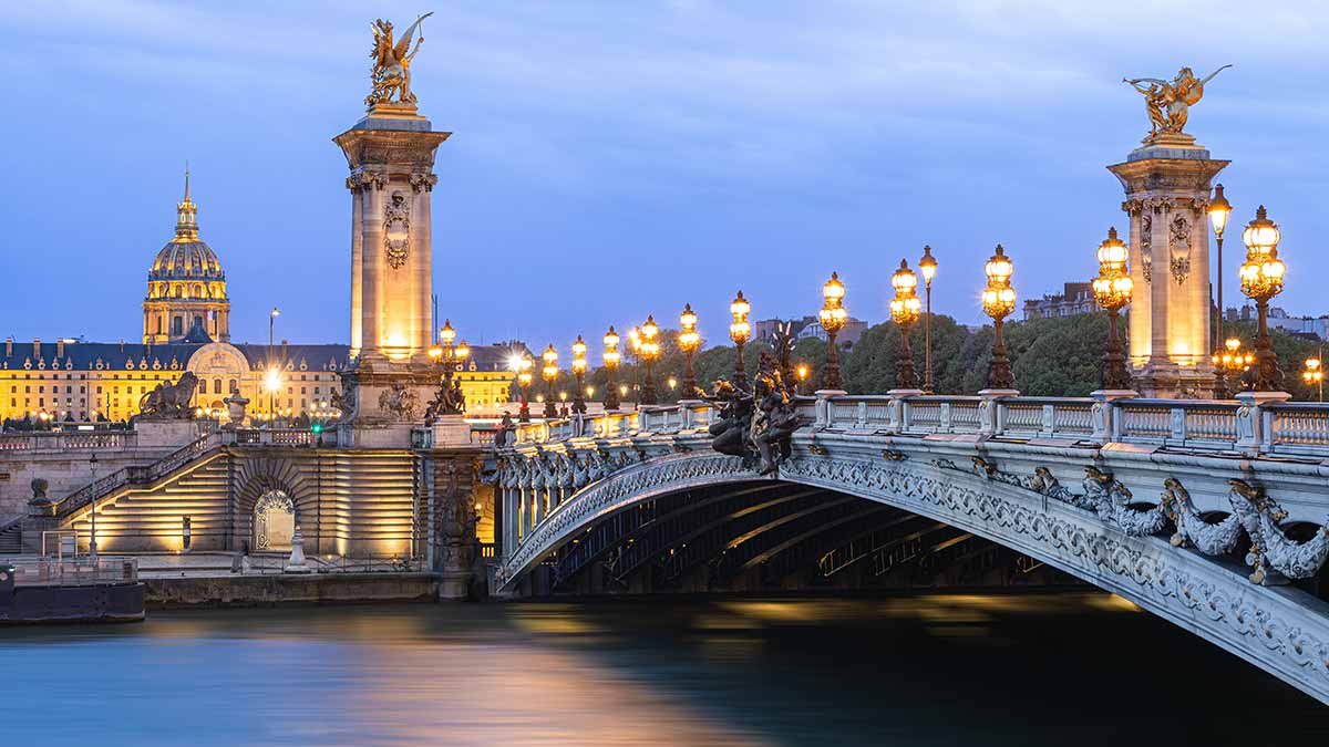 Pont Alexandre III bridge and Les Invalides in Paris at sunset.