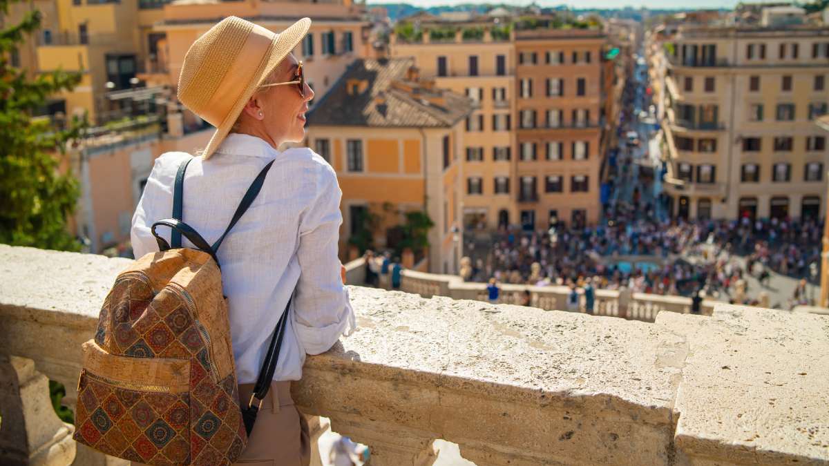 woman standing on a landing looking over a Roman streetscape
