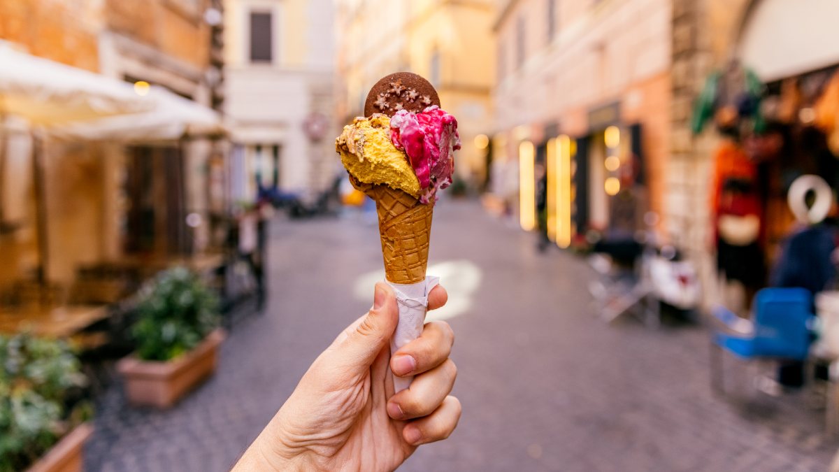 person holding a gelato up in an alleyway in Rome