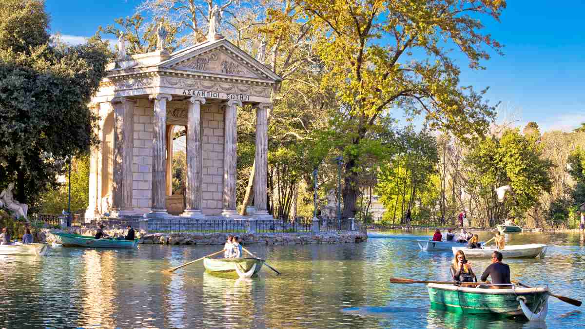 people boating on a lake by a Roman building