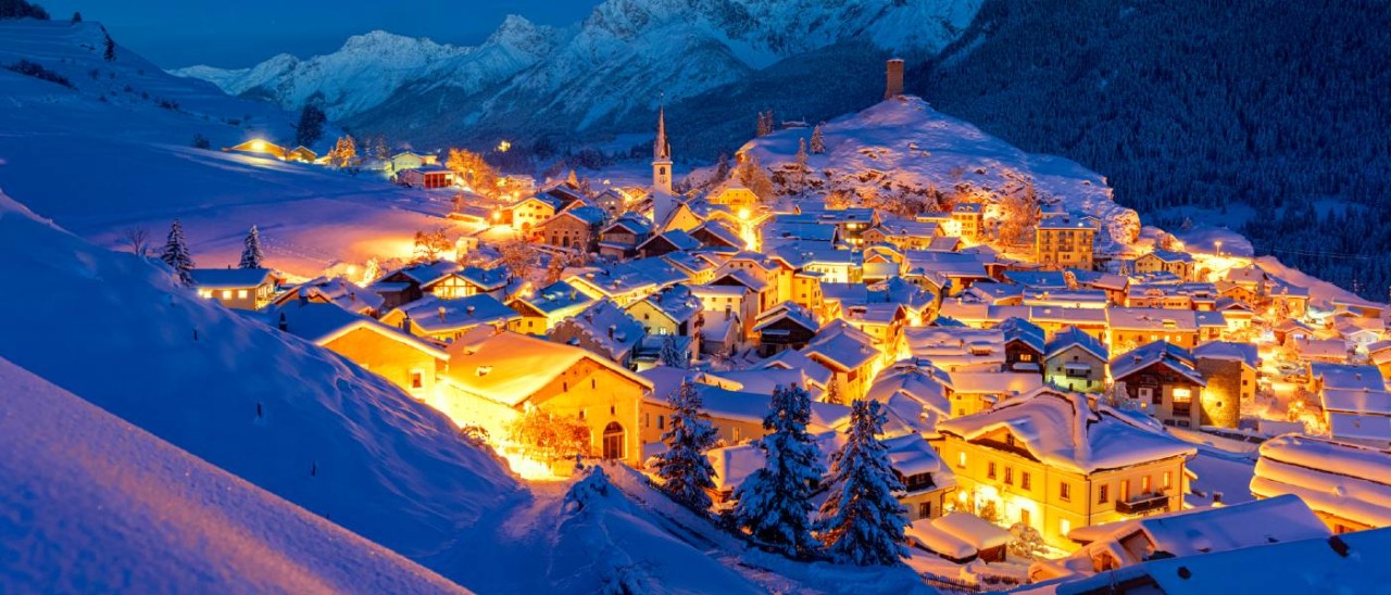 snowy alpine town lit at night