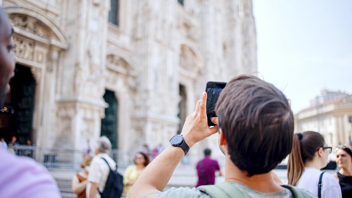 Tourist taking photo in front of Duomo in city of Milan in Italy