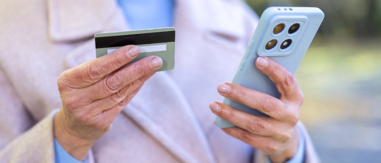 older woman holding a credit card and a smartphone