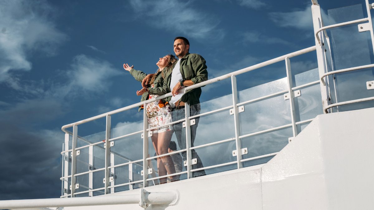 man and pregnant woman on upper level of cruise ship smiling