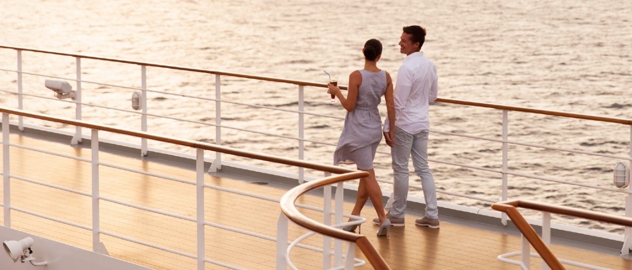 man and woman holding hands and walking on cruise ship